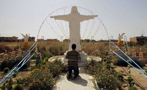 An Iraqi Christian prays in front of a gypsum statue of Jesus Christ made by a local resident at the town of Qaraqush in Nineveh
