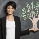 Asian woman and chalk money tree drawing on blackboard.