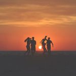 couples playing on beach at sunset