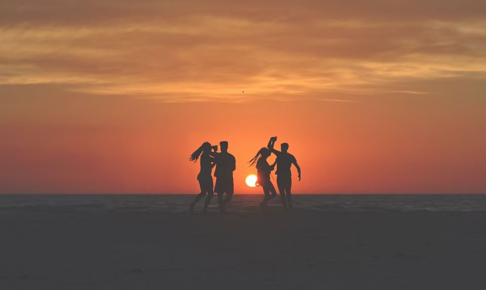 Couples playing on beach at sunset