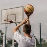 man putting ball in basket net
