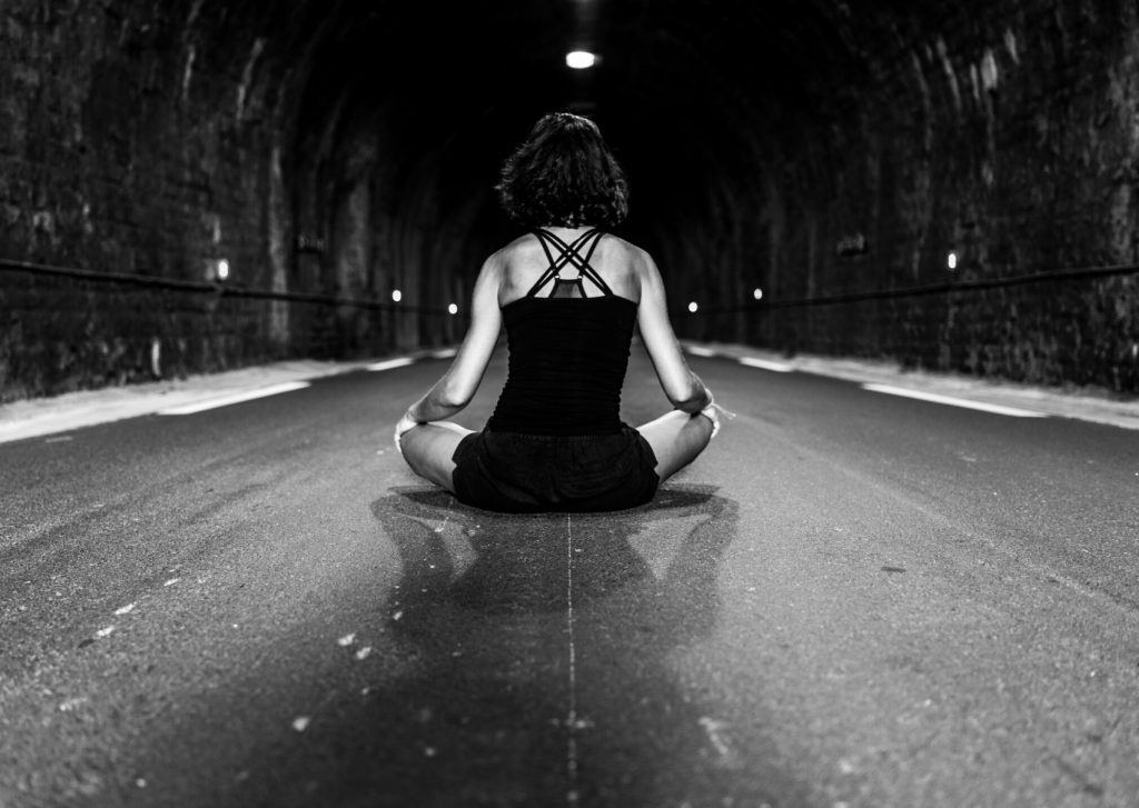 lady meditating on road in tunnel