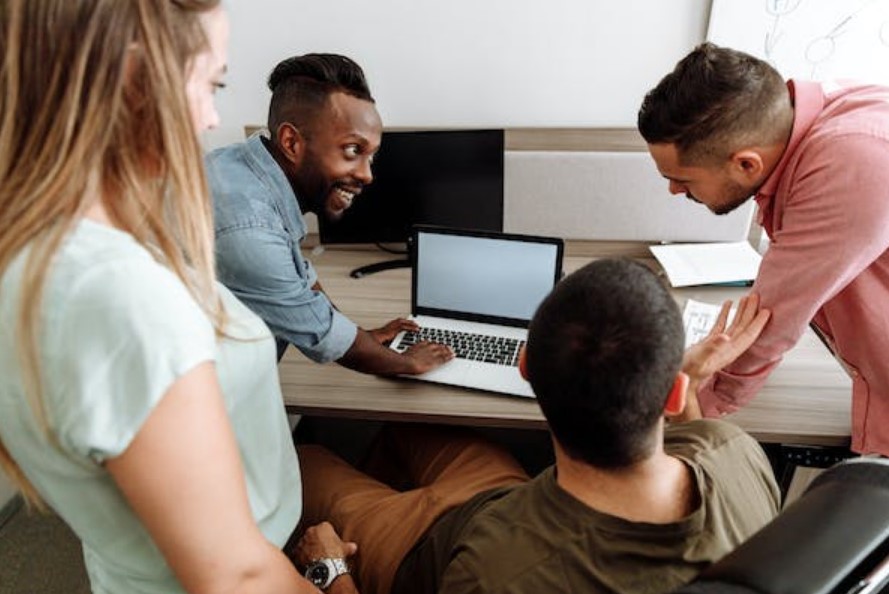 Group of people happily discussing infront of a laptop