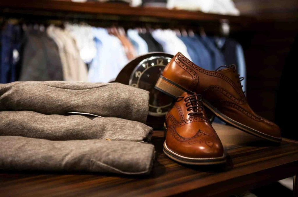 pair of brown leather wingtip shoes beside gray apparel