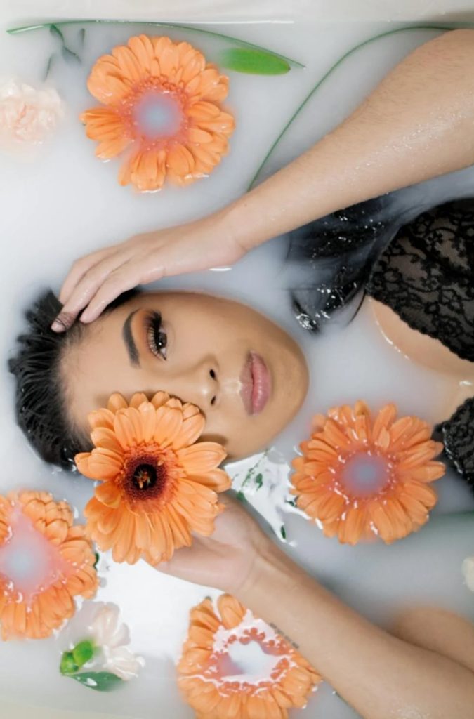 woman in bathtub with orange petaled flowers