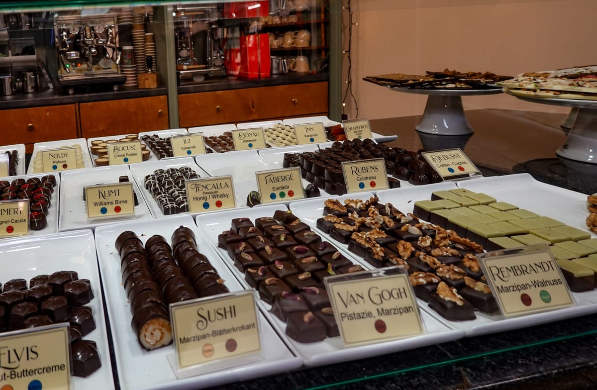 Gourmet artisan chocolates neatly arranged on trays in a confectionery shop display counter.