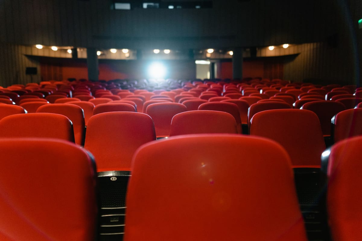 Rows of empty red seats inside a dimly lit cinema theater ready for an international movie screening.