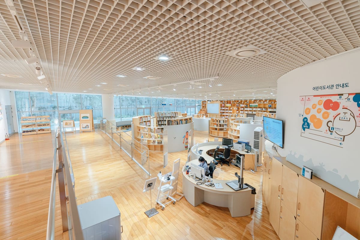 Spacious modern library interior with curved wooden bookshelves and open study areas for continuous learning.