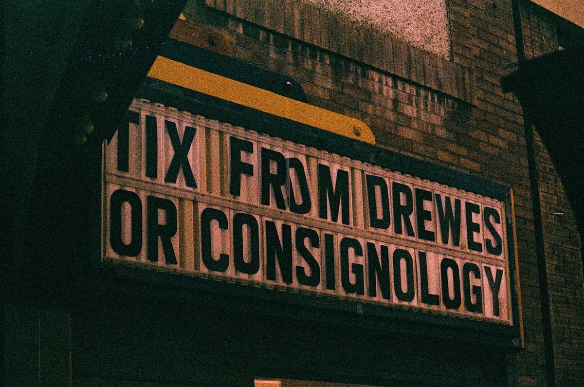 Vintage theater marquee sign advertising ticket sales on an old brick building exterior.